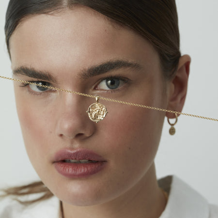 Model holding gold Aphrodite necklace.